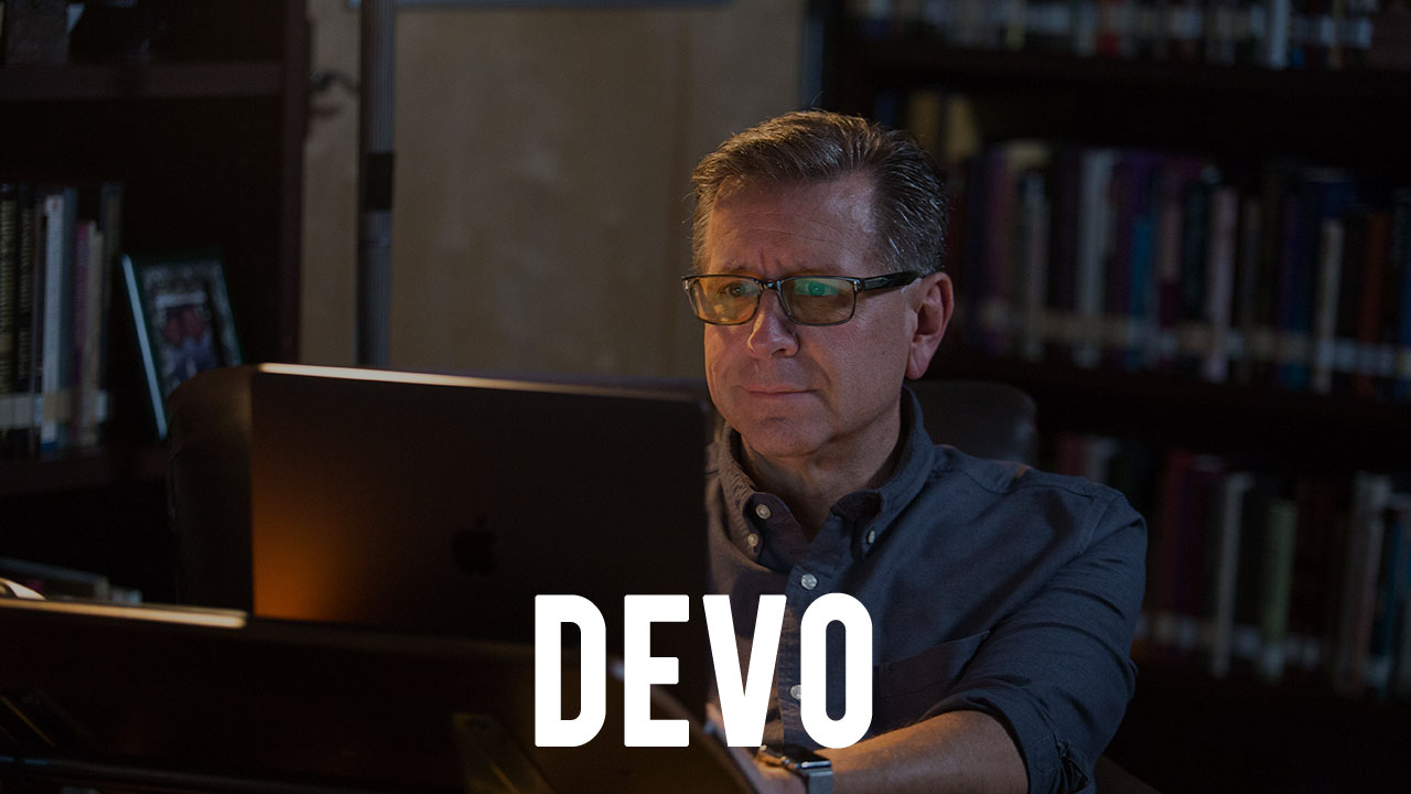 the word "DEVO" overlayed upon an image of Pastor Mike Fabarez in his study writing at a computer
