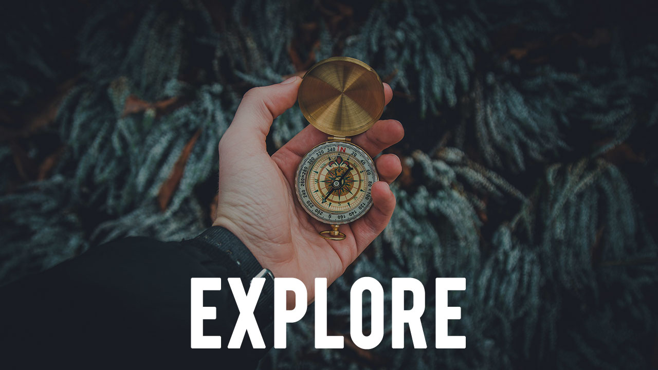 the word "EXPLORE" overlayed upon an image of a hand holding a compass in the woods