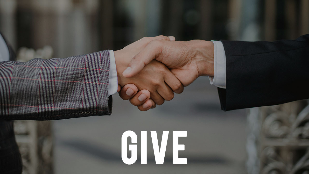 the word "GIVE" overlayed upon an image of two people shaking hands